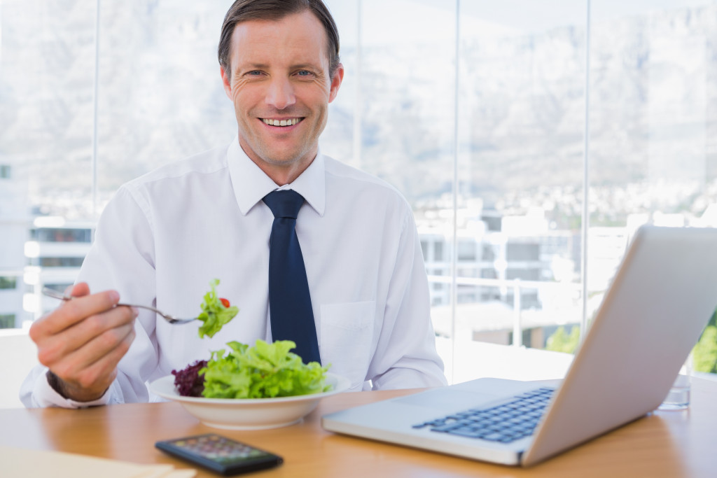a businessman eating a salad while working